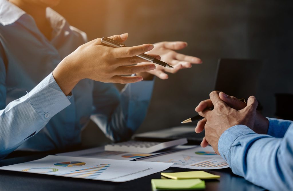 Dos personas hablando con documentos sobre la mesa